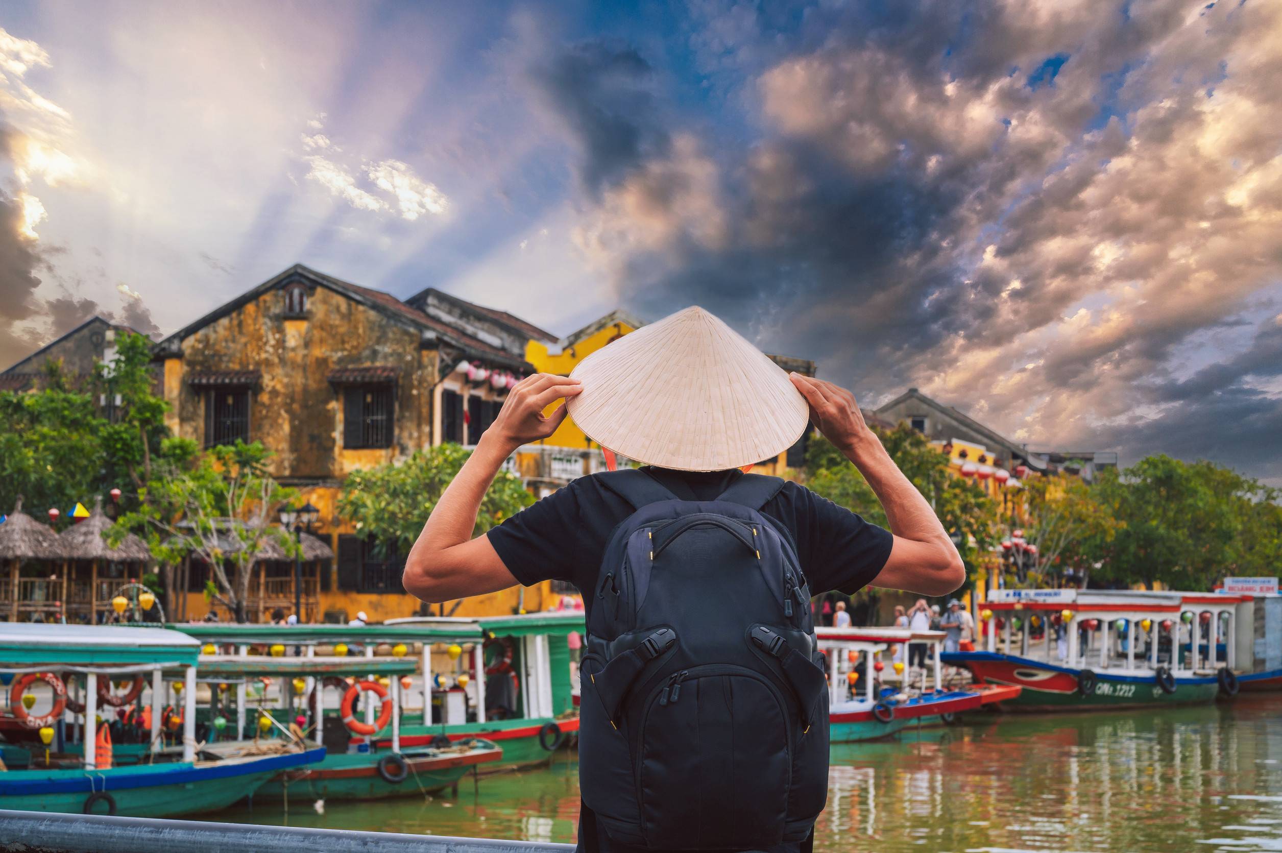 Back of male tourist traveler in Vietnamese hat on a bridge in old town in Hoi An in Vietnam in Asia
