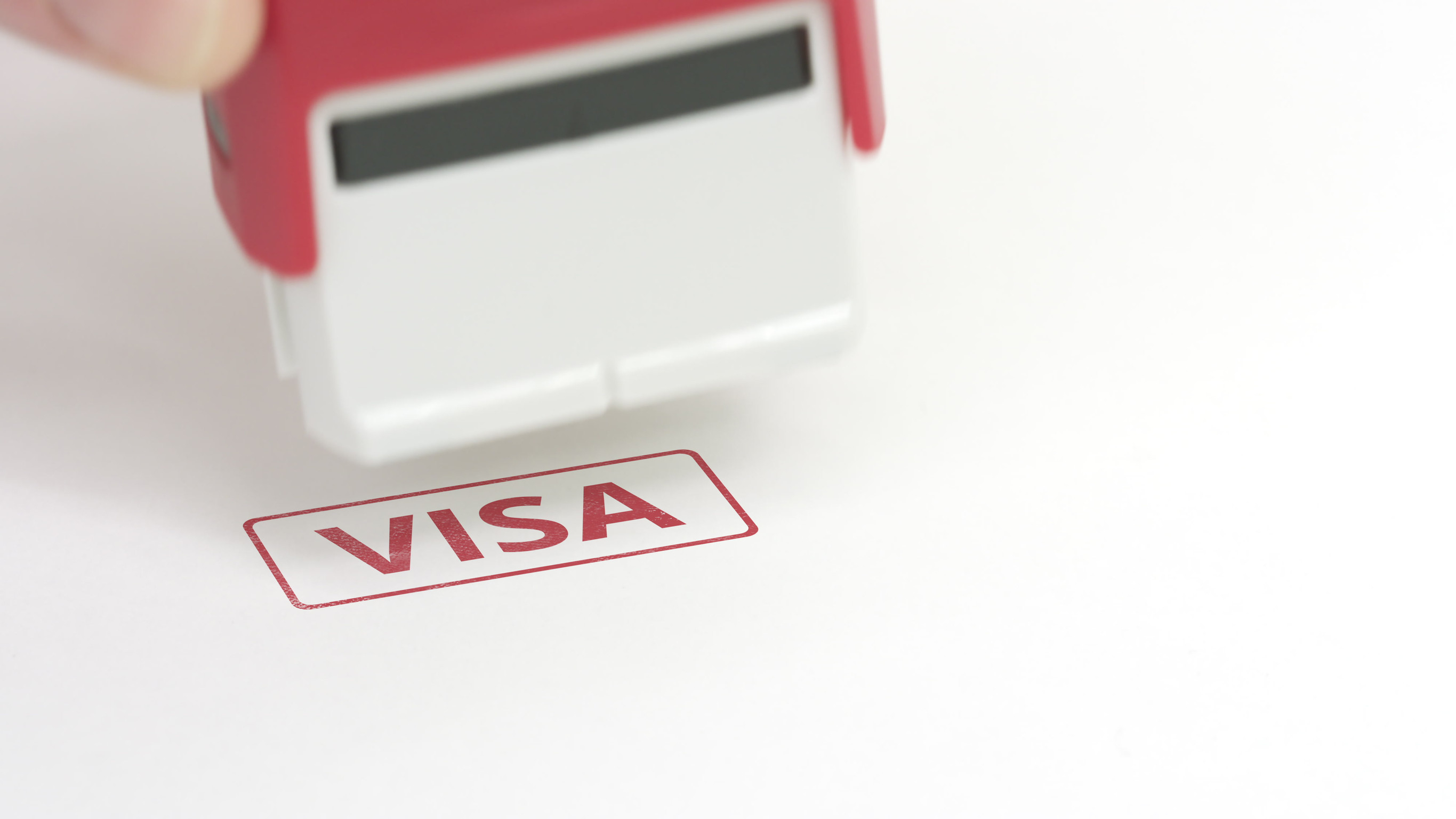 Putting red visa rubber stamp on the paper close up shot