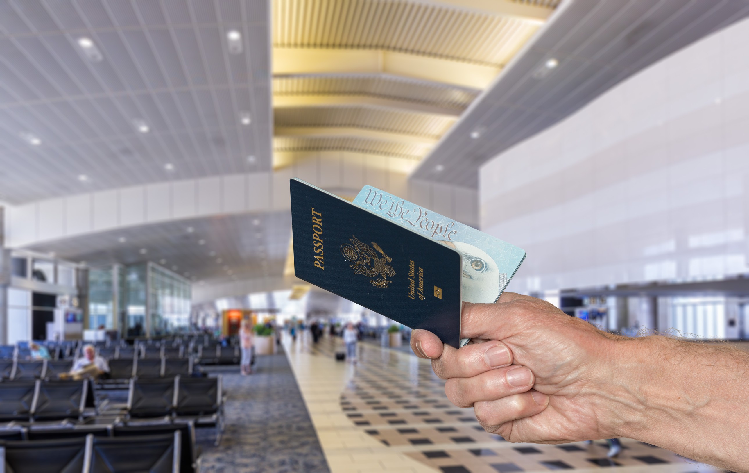 Senior caucasian arm holding an open USA passport to show to official in airport terminal