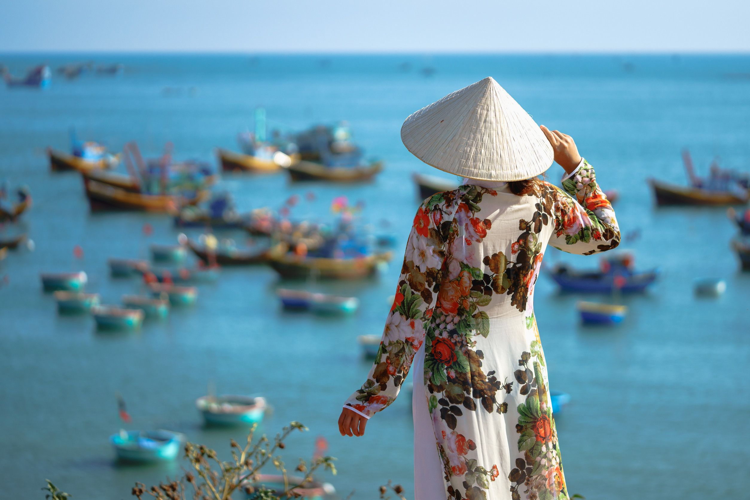 Back of male tourist traveler in Vietnamese hat on a bridge in old town in Hoi An in Vietnam in Asia