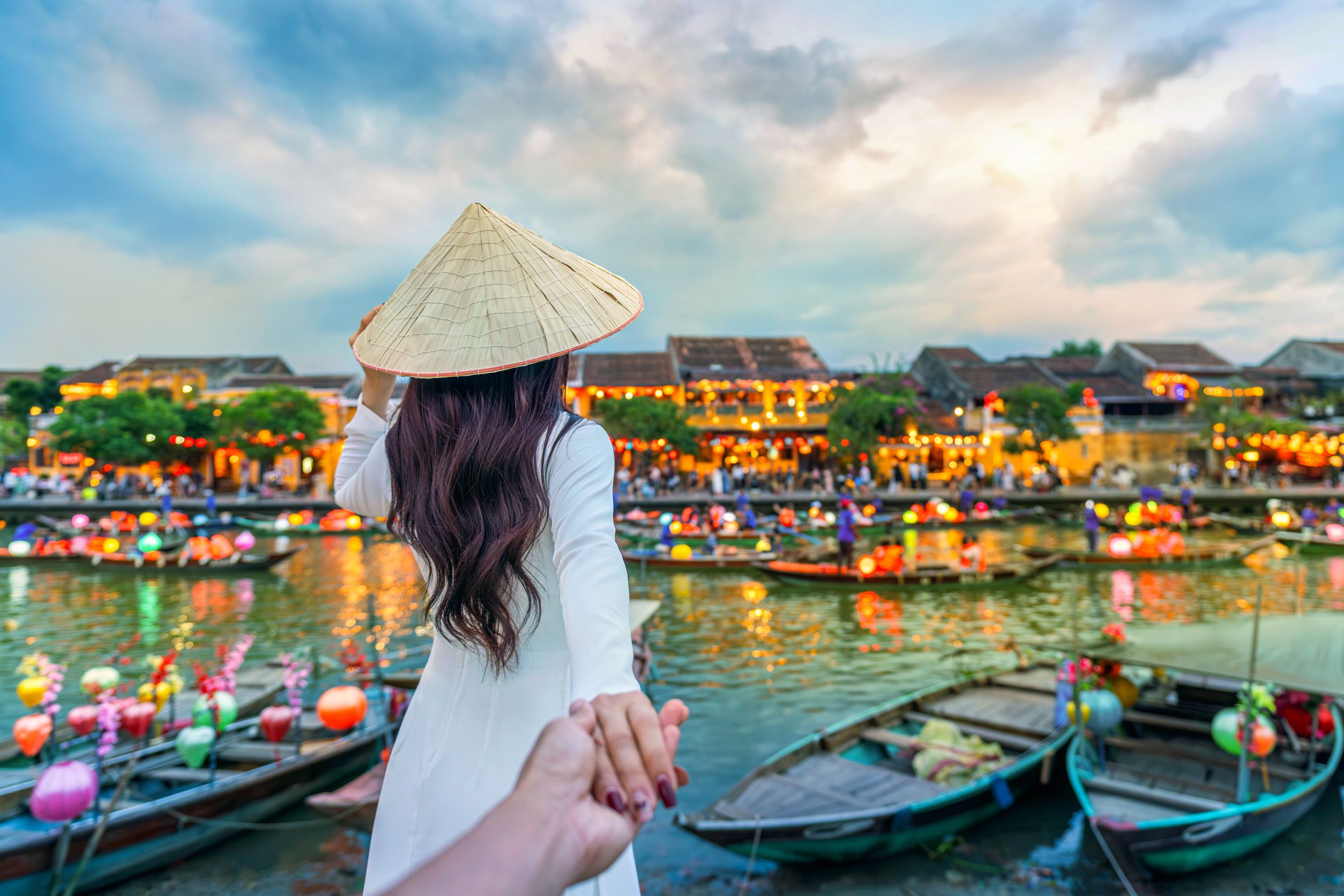 Women tourist holding man's hand and leading him to Hoi An ancient town, Hoi An city in Vietnam